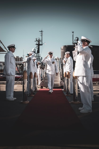 Naval officer saluting on a red carpet during a military ceremony on a ship